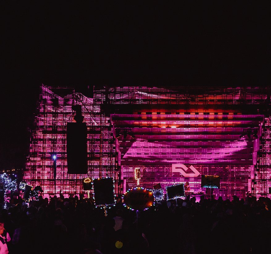 A festival stage bathed in pink and purple light